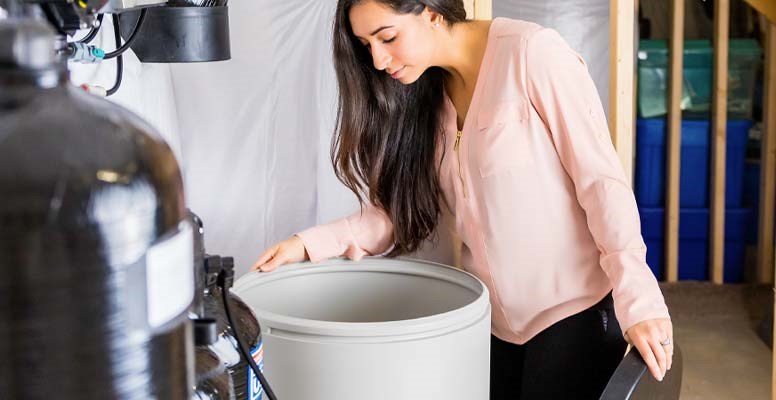 Woman checking water softener salt in brine tank