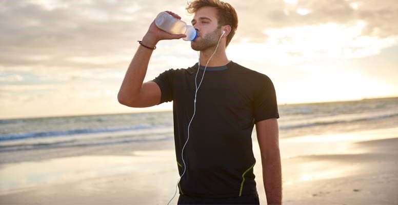 Man working out and drinking water on beach